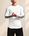 White long-sleeve T-shirt with charcoal sleeve stripes, worn against an ivory wall.