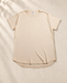 Beige oversized crew-neck T-shirt with a curved hem laid on ivory linen.