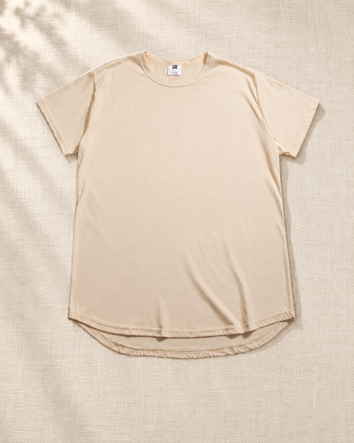 Beige oversized crew-neck T-shirt with a curved hem laid on ivory linen.