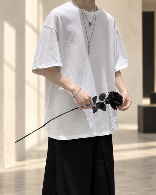 White oversized crew-neck T-shirt worn with black trousers in an ivory gallery.
