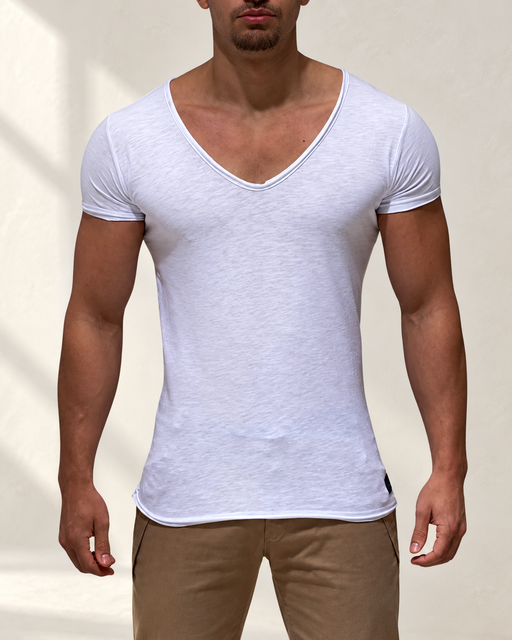 White deep V-neck short-sleeve T-shirt worn against a softly lit ivory wall.