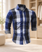 Blue, black and grey plaid shirt with rolled contrast cuffs displayed in a softly lit wardrobe interior.