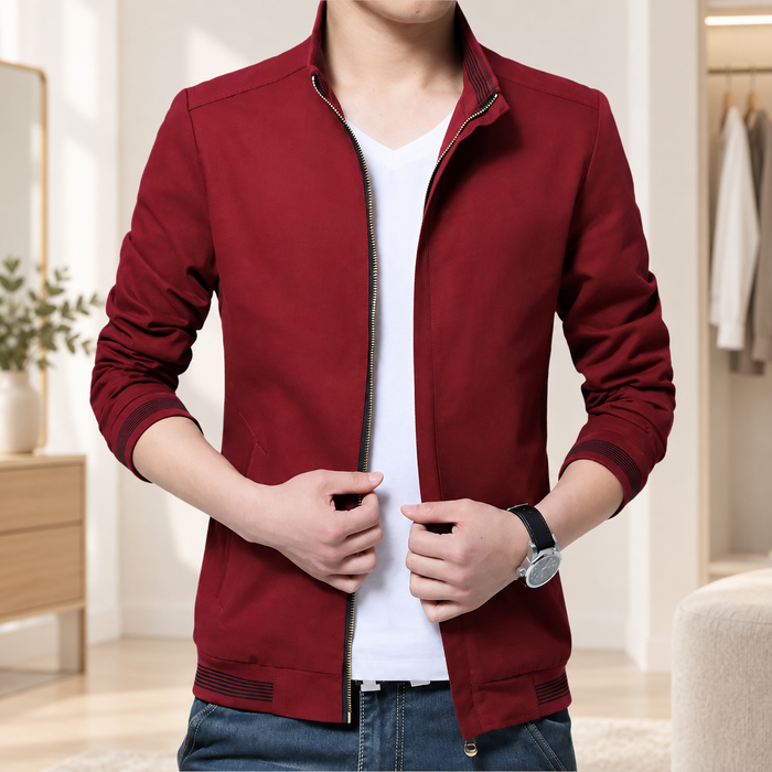 Man wearing an open burgundy jacket with striped cuffs and hem over a white shirt.