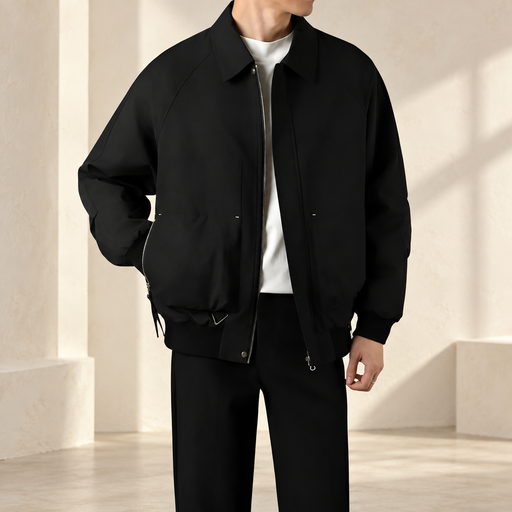 Man wearing a loose black zip jacket with a broad collar over a white shirt.