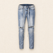 Light blue distressed jeans with long waist ties and two ripped knees on ivory linen
