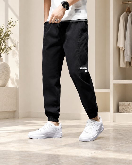 Black tapered trousers with elastic ankle cuffs and white leg lettering.