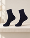 Pair of plain dark navy ankle socks on an ivory linen shelf.