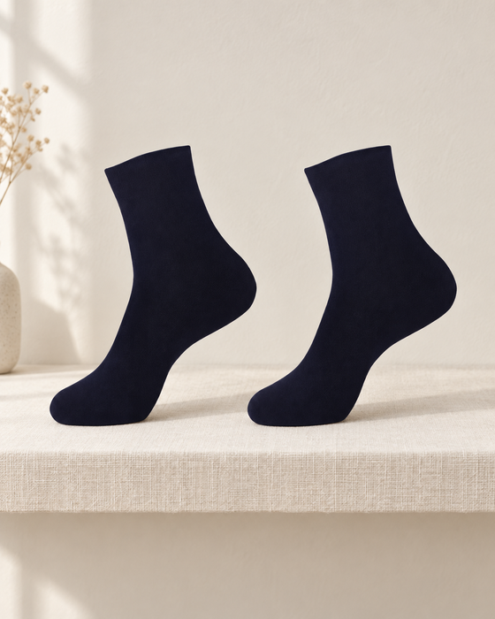 Pair of plain dark navy ankle socks on an ivory linen shelf.