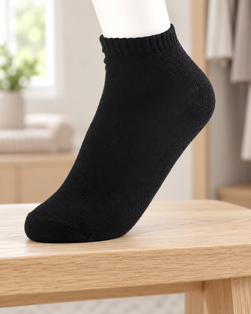 Black ankle sock on a white display foot resting on a pale wooden bench.