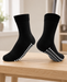 Pair of black socks with white oval sole grips displayed on a pale wooden bench.