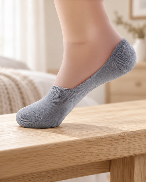 Light grey no-show sock on a display foot resting on a pale wooden bench.