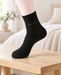 Black crew sock with grey Bamboo lettering on a display foot above a wooden bench.