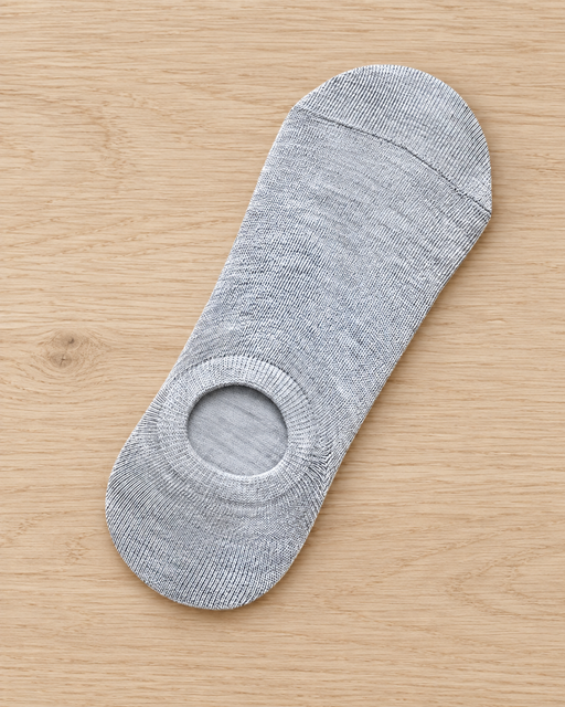 Single light grey no-show liner sock laid flat on a pale wooden bench.