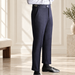 Navy high-waisted trousers with a side waist buckle, shown from a three-quarter angle in an ivory interior.
