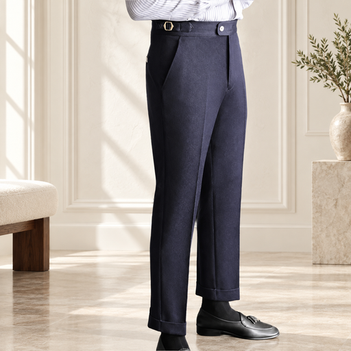 Navy high-waisted trousers with a side waist buckle, shown from a three-quarter angle in an ivory interior.