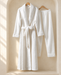White textured robe with a tie belt and matching trousers hanging in an ivory dressing alcove.