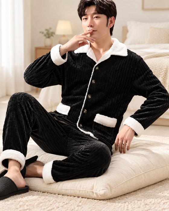 Black ribbed plush pajama set with white collar, pocket and cuff trims, worn on an ivory cushion.