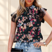 Black floral blouse with lace cap sleeves against warm ivory background