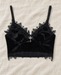 Black velvet camisole with lace trim and a silver-tone cross pendant on ivory linen.