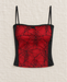Red and black spiderweb-pattern camisole with thin straps, displayed on ivory linen.