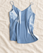 Light-blue camisole with thin straps and a V neckline, displayed on ivory linen.