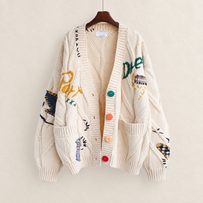 Cream patchwork cardigan on a wooden hanger