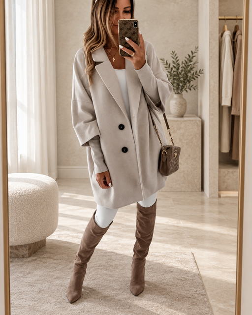 Stone-grey oversized coat with two black buttons worn in a pale stone dressing room.