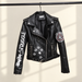 Black printed biker jacket hanging against a warm ivory wall