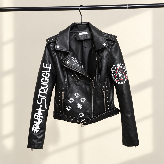 Black printed biker jacket hanging against a warm ivory wall