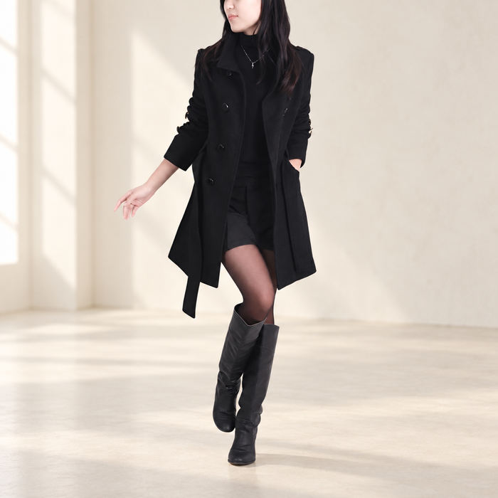 Long black coat with open lapels worn in an ivory interior