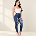 Dark blue distressed skinny jeans worn with a white top in an ivory studio