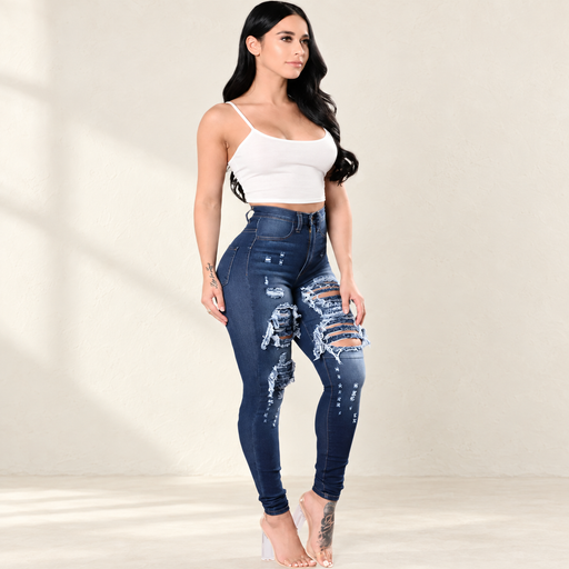 Dark blue distressed skinny jeans worn with a white top in an ivory studio