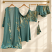Green botanical satin sleepwear set on wooden hangers against ivory wall.