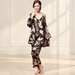 Woman wearing black and blush printed three-piece sleepwear in ivory interior.