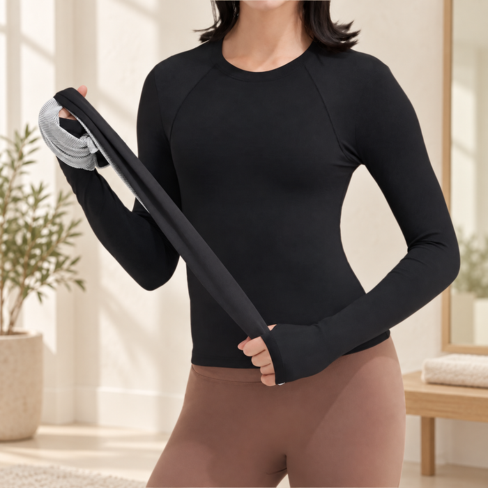 Black long-sleeved running top with thumb-hole cuffs, worn with brown leggings in an ivory interior.