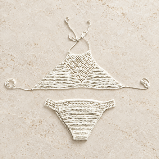 Ivory crochet two-piece swimwear arranged on a warm stone surface.