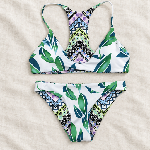 Leaf and geometric-print two-piece swimwear on ivory linen.