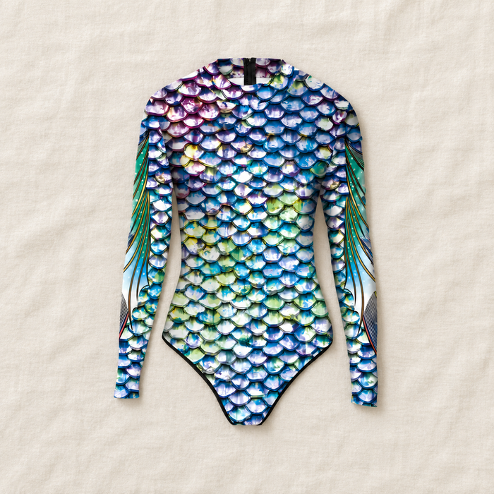 Long-sleeve multicolour scale-print swimsuit laid on ivory linen.