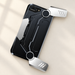 Black phone case with extended silver grips on a warm ivory desk.
