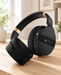 Black over-ear headphones with gold-coloured headband details on a wooden desk in an ivory study.