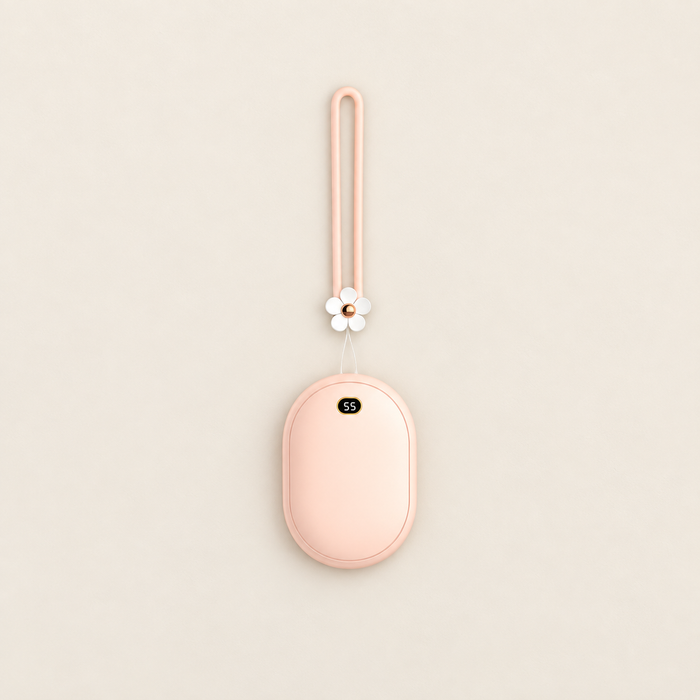 Peach oval power bank with flower wrist strap lying on an ivory surface