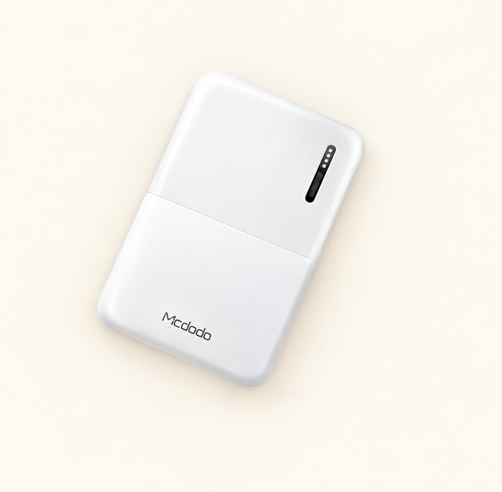 White Mcdodo power bank with four small indicator openings on an ivory surface.