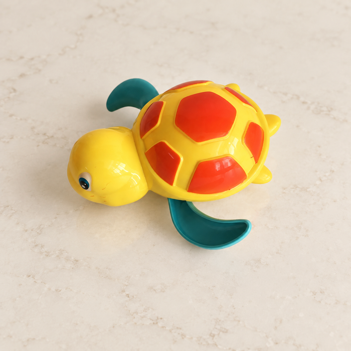 Yellow turtle bath toy with teal flippers on ivory countertop