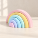 Pastel silicone rainbow stacking toy on an ivory tabletop