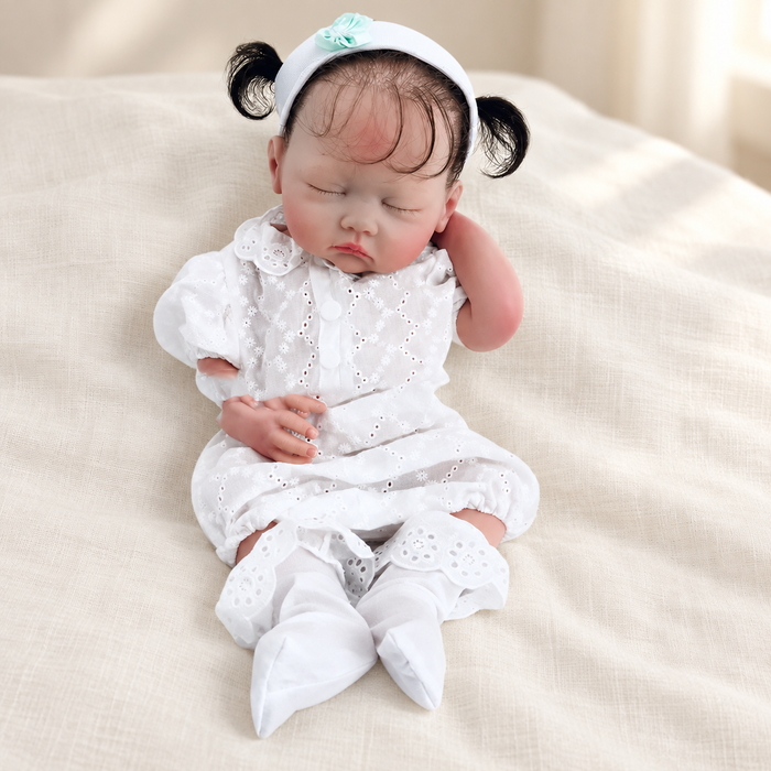 Sleeping doll in a white outfit on ivory linen