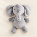 Grey plush elephant lying on an ivory surface