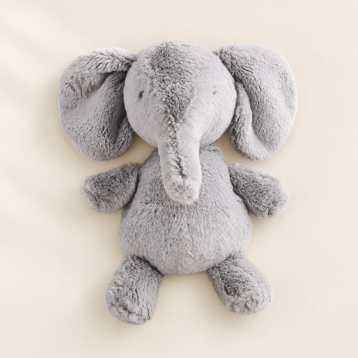 Grey plush elephant lying on an ivory surface