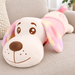 Pink dog-shaped plush cushion with multicoloured ears on a fabric sofa.