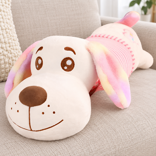 Pink dog-shaped plush cushion with multicoloured ears on a fabric sofa.