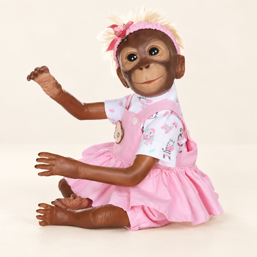 Monkey doll in pink dress seated against ivory background